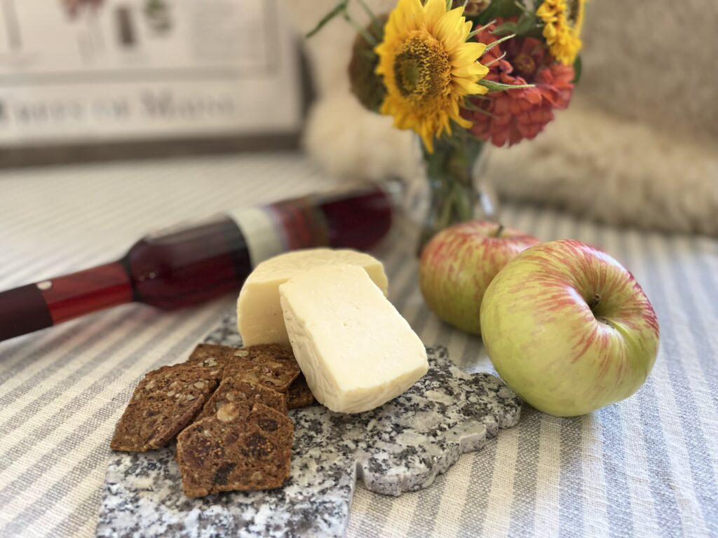 Cheese, crackers, and apples displayed on a table setting