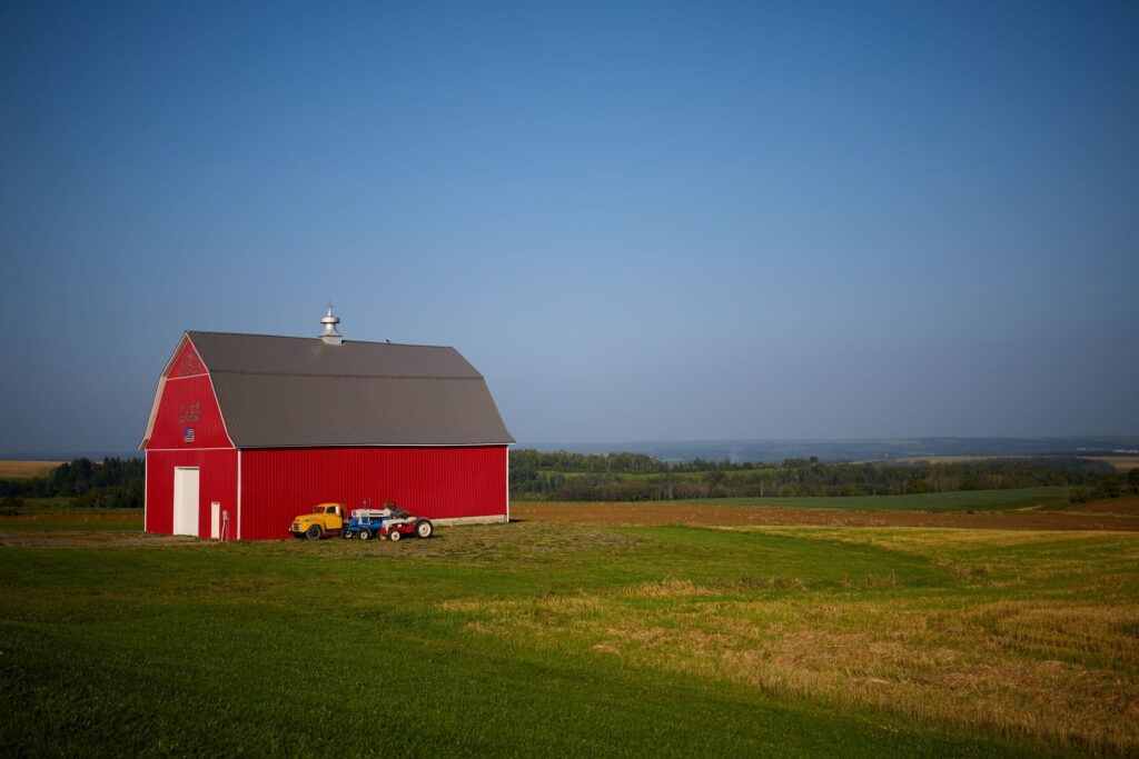 Lajoie Farm in Maine, showcasing a vibrant red barn, surrounding farmland, and blue sky.